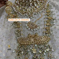 An absolutely regal bridal set featuring intricate Kundan work with pearl detailing. This rental set comes with a choker, a layered necklace, a passa, maang tikka, and matching earrings for a complete look.