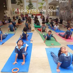 A large group of students participates in an outdoor yoga session, finding a moment of calm and focus together. I integrate practices like yoga to teach children balance, discipline, and mindfulness from an early age.