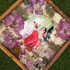 A full view of a varmala preservation frame, where I arranged the couple's wedding flowers around their favorite photo. The rich purple and white petals, combined with a natural wood frame, create a piece that is both rustic and elegant.