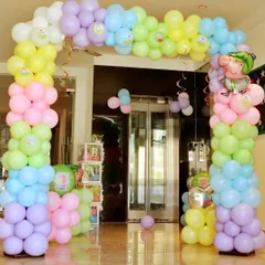 An indoor balloon arch in pastel rainbow colors for a Peppa Pig party. The Peppa and George foil balloons add the perfect finishing touch.