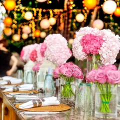 Beautiful floral centerpieces with pink hydrangeas and roses. The bokeh of the background lights adds a dreamy and festive feel to this decor shot.
