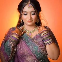 A beautiful portrait of the bride-to-be in her purple and green lehenga, with warm lighting creating a lovely glow.