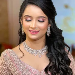 A close-up of the bride's soft glam makeup, featuring pink eyeshadow and a glossy lip. The diamond jewellery adds a touch of sparkle that complements her radiant skin.