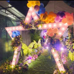 A large, star-shaped entrance arch with integrated lighting. This custom structure was decorated with florals and balloons to create a grand and whimsical entryway for an evening party.