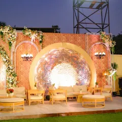 This outdoor reception stage combines intricate patterns with soft, romantic florals. The central backlit mandala creates a warm focal point, while elegant lounge seating invites guests to relax and enjoy the evening.