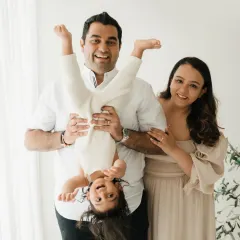 A father playfully holds his laughing child upside down during a fun family photoshoot in my studio. These lifestyle sessions are all about capturing the real, silly moments that define your family.