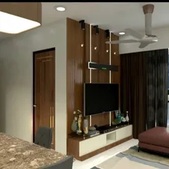 A modern living room design featuring a wood-panelled TV wall with a soundbar, a plush leatherette sofa, and a marble-top dining table. The use of a large mirror with a geometric pattern adds depth and a touch of glamour to the space.