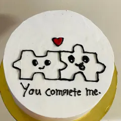 A cute puzzle-piece themed cake with the message "You complete me."