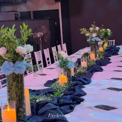 This classic blue and white dining setup is perfect for a refined celebration. We used tall glass vases with blue and white floral arrangements, a deep blue table runner, and pillar candles to create a crisp and elegant look.