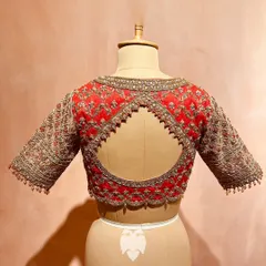 The back of a rich red raw silk blouse, featuring a distinctive checks pattern brought to life with katdana, zari, and sequins.