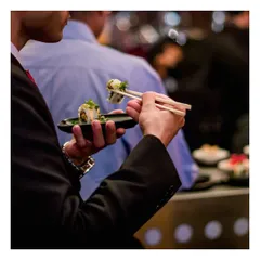 A guest enjoys a piece of our freshly made sushi. Our canapés are designed to be elegant and easy to eat while standing, allowing guests to socialize without interruption.