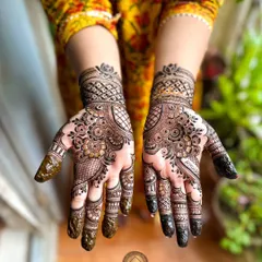 A lovely Karwa Chauth henna design. This symmetrical pattern features intricate floral and paisley work that covers the palm and wrist, perfect for the festive occasion.