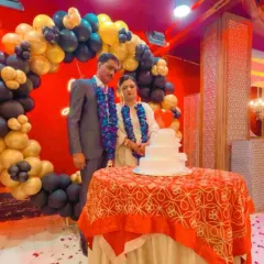 The happy couple celebrating their 25th anniversary in front of a black and gold circular balloon arch. I set up a dedicated cake-cutting table to complete the scene.