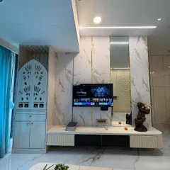 A glimpse of a finished living room in Mumbai, integrating a custom TV unit with marble-finish panels and a beautifully crafted pooja mandir with jaali work. The design balances modern aesthetics with traditional values.