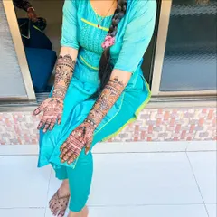 A full view of a happy client with her engagement henna on both arms and feet. The design is consistent and flows beautifully from hands to feet.