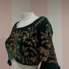A classic combination of zardosi embroidery on a rich green velvet. This blouse features a wide neckline and full-length sleeves covered in intricate floral patterns.