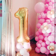 A large, gold foil number "1" balloon stands tall, marking a milestone first birthday. This simple but impactful decoration is a classic element for celebrating this special day.