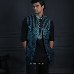A closer view of the teal embroidered jacket over a black Achkan, highlighting the intricate patterns and the modern layering.