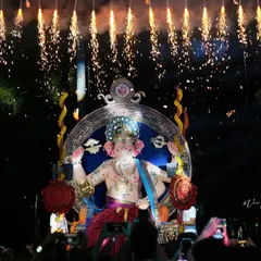 The Sanpada Cha Raja idol illuminated by a shower of fireworks. This image captures the spectacular and celebratory nature of the night processions.