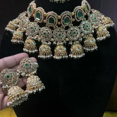 This image shows the beautiful detail of the choker necklace with its dangling jhumkas and pearl accents. It's a high-quality piece that looks heavy but is designed to be comfortable to wear throughout the event.