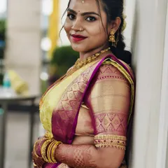 A smiling portrait of the bride, giving a closer look at the intricate zari work on the sleeves of her blouse.