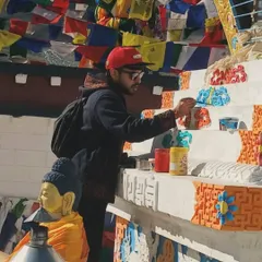 A closer look at the detail work. I am carefully applying paint to the intricate patterns on the base of the Stupa, fully focused on the task at hand in this high-altitude environment.