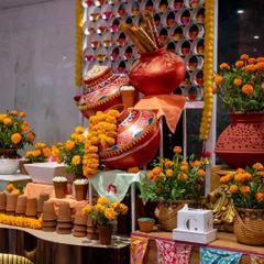 A vibrant and rustic food station decorated with terracotta pots, marigold flowers, and colourful textiles. This setup is designed to create a warm, festive, and authentically Indian atmosphere.