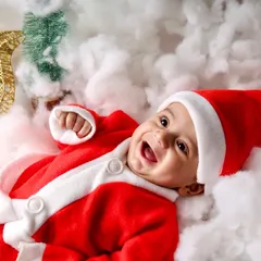 The happiest little Santa! This baby's joyful laugh is infectious in this adorable Christmas-themed close-up, complete with a Santa suit and festive reindeer prop.