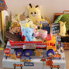The full view of the 'Project Steel Express' hamper. It features a Bob the Builder cutout, a toy truck filled with gifts, and custom road signs pointing to Borivali and Taloja, adding a personal touch for the family.
