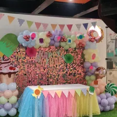 The main table at a Candyland themed party, featuring a shimmering backdrop and a colorful table skirt, ready for the birthday cake and sweets.