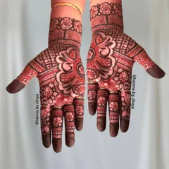 A rich, red-stained mehendi with a bold central flower. The design is filled with intricate details and a Greek key-style border.