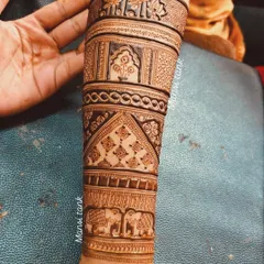 A beautiful example of Indian bridal mehendi extending up the forearm. The design is divided into sections with different patterns, including elephants, architectural jharokhas, and floral motifs.