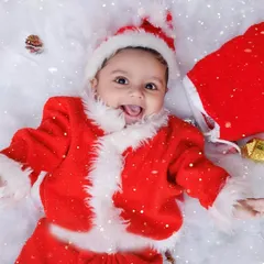 A happy baby Santa lies in a bed of snow, surrounded by presents. This is pure holiday cheer!