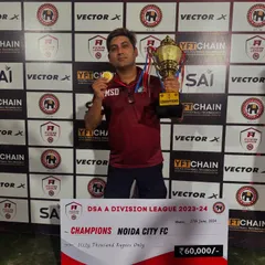 Our director holding the medal and trophy alongside the winner's cheque for the DSA A Division League 2023-24. We don't just play, we win.