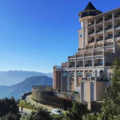 A clear day view of the ITC Tavleen resort in Chail, showcasing its commanding position in the Himalayan landscape. The building's tiered structure ensures that many rooms and balconies offer panoramic views.