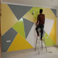 Our painter carefully works on a geometric accent wall in a bedroom. This design uses a vibrant palette of yellow, lime green, grey, and white to create a cheerful and energetic atmosphere.