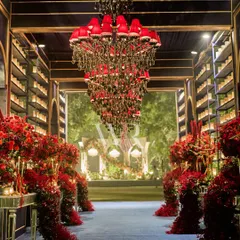 A dramatic entrance for a night of romance. I designed this tunnel with midnight blue walls, a matching carpet, and an explosion of red florals, all leading towards a magnificent red-shaded chandelier.