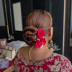 I love creating classic bridal buns that are both secure and beautiful. This intricate twisted updo is accented with vibrant red roses and delicate baby's breath, making it a timeless choice for the main wedding ceremony.