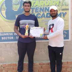Niraanjan Singh receives his first AITA CS U-18 singles title trophy from a tournament official. This win is a testament to his hard work and the support from his coaching team.