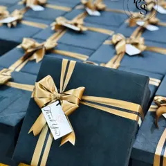 A close-up of our premium corporate gift boxes. These deep green velvet boxes are finished with a custom-branded "Thank You" tag and a striking gold ribbon, designed to leave a lasting impression on valued clients.