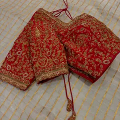 A classic red bridal blouse is timeless for a reason. This piece is covered in heavy, intricate zardosi and thread work, designed to be the perfect regal complement to a wedding saree.