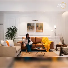 We believe living spaces should be both elegant and comfortable. Here, classic wall mouldings and warm lighting create a sophisticated backdrop for the rich tan leather sofa and curated artwork, resulting in an inviting atmosphere for relaxation and socializing.