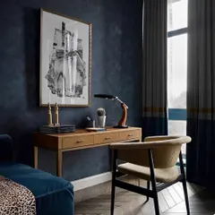 This moody and elegant home office corner uses a deep blue textured wall as a backdrop. The simple wooden desk and classic chair create a sophisticated, distraction-free zone for focused work.