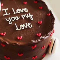 A petite chocolate cake with a big message. Decorated with mini hearts and macarons, this cake is a sweet way to say "I love you my love."