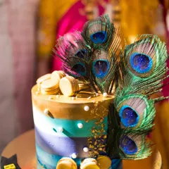 A stunning peacock-themed cake, adorned with real peacock feathers and golden accents. This was the centerpiece of a beautiful Radha-Krishna themed baby shower.