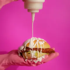 This shot for Dirty Burger is all about fun and breaking the rules. The vibrant pink background and dramatic sauce drizzle create a playful, high-energy image that perfectly matches the brand's edgy persona.
