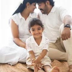 A beautiful family portrait with the parents sharing a loving glance in the background while their daughter smiles at the camera. A perfect mix of posed and candid.