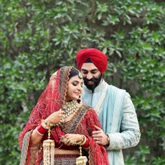 A beautiful moment between a Sikh bride and groom, showcasing the intricate details of the bride's red lehenga and traditional jewelry.