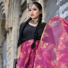 A full-length view of the modern ethnic look. The makeup is kept fresh and clean with a defined eye and a mauve lip, letting the outfit and unique braided hairstyle stand out.