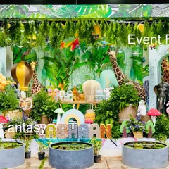An incredibly detailed and lush jungle setup for Eshaan's birthday. The scene is filled with hanging foliage, a variety of animal figures like tigers and flamingos, and small water pools to create a truly immersive tropical jungle experience.